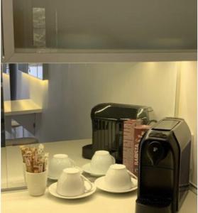 a kitchen counter with a toaster and saucers and a coffee maker at studio in vila- natural 22 C ! in Breaza de Sus