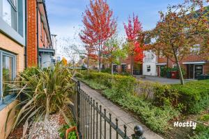 a fence in front of a street with trees at Puffin Way - Comfortable, spacious house with parking in Reading