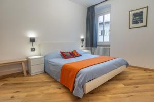 1 dormitorio con 1 cama con manta naranja y ventana en DolomiApartments - Campanil 1 e 2, en Predazzo