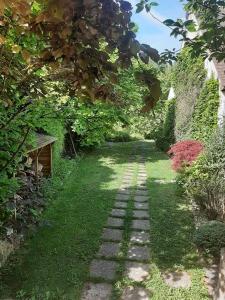 een tuin met een stenen pad in het gras bij Au Chat Perché espace familial in Mareil-sur-Mauldre