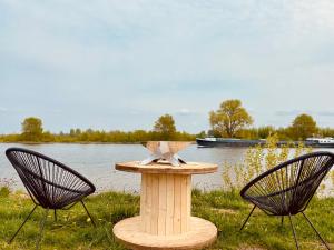 una mesa con dos sillas junto a un lago en Bell Tent en Heerewaarden