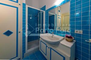 uma casa de banho em azulejos azuis com um lavatório e um chuveiro em 24PN - Vecchio Marino splendido villino vista mare em Palau