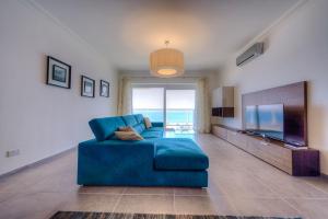 ein Wohnzimmer mit einem blauen Sofa und einem TV in der Unterkunft Seafront Luxury Apartment with Pool in Sliema