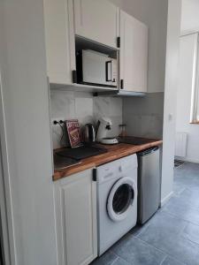 a kitchen with a washing machine and a microwave at Charmant appartement hyper centre métro gare in Toulouse
