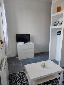 a living room with a white table and a tv at Charmant appartement hyper centre métro gare in Toulouse