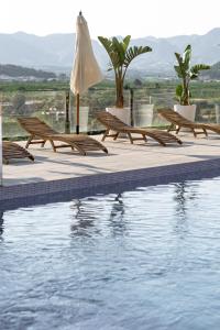 une piscine avec bancs et parasol à côté de l'eau dans l'établissement Finca de l’Anglés. Levante, à Potríes