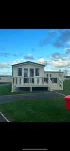 a white house with a porch and a fence at Holiday home by the sea in Leysdown-on-Sea