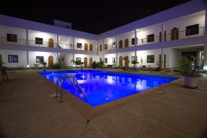 uma grande piscina com água azul à noite em Hôtel le Relais de Kolda em Kolda