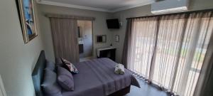 um quarto com uma cama e uma grande janela em Housemartin Guest House em Klerksdorp