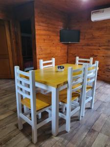 einem Holztisch mit vier Stühlen und einem TV in der Unterkunft Cabaña Los Acacios II Lobos in Lobos