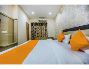 sypialnia z dużym łóżkiem z pomarańczowymi poduszkami w obiekcie Hotel Rukmani Palace, Sri Ganganagar w mieście Gangānagar