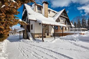 a house covered in snow with footprints in the snow at Leśny Dworek in Białka Tatrzańska