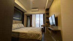 a hotel room with a bed and a television at Meisterstadt Pollux Habibie Apartment by uhomeid in Batam Center