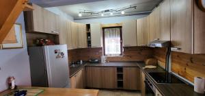 cocina con armarios de madera y nevera blanca en Biocinovici vikendica en Kolašin
