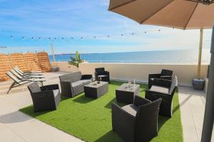 une terrasse avec des chaises, une table et un parasol dans l'établissement ROOFTOP DE LA PLAGE Charming apartment on seafront with superb roof terrace, à Cannes