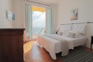 - une chambre avec un grand lit blanc et une grande fenêtre dans l'établissement ROOFTOP DE LA PLAGE Charming apartment on seafront with superb roof terrace, à Cannes