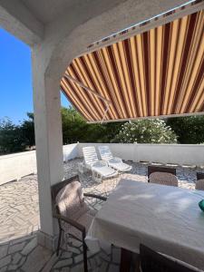 a patio with a table and chairs and a large wooden screen at Apartment Tea in Rab
