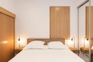 a bedroom with a large white bed with two lamps at Le charmant de Catherine in Nancy