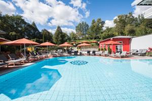 einen Pool in einem Hotel mit Stühlen und Sonnenschirmen in der Unterkunft Hotel St. Wolfgang in Bad Griesbach