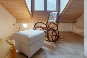 Habitación con silla y taburete en el ático en DolomiApartments - Appartamento Orso Bruno, en Predazzo