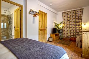 a bedroom with a large bed and a bathroom at La Vieja Botica in Canillas de Aceituno