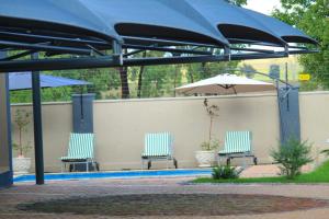 two blue chairs and an umbrella on a patio at Tranquility Guesthouse in Standerton