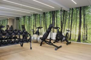 una sala de fitness con equipos de ejercicio frente a un bosque en AR Prestige Penthouse - Noho, en Bérgamo