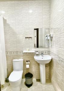 La salle de bains est pourvue de toilettes et d'un lavabo. dans l'établissement Zahid Inn, à Tachkent