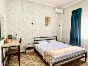 a bedroom with a bed and a desk and a table and a bed at Zahid Inn in Tashkent
