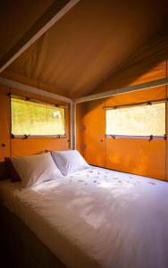 a bedroom with a white bed with two windows at Camping Vilanova Park in Vilanova i la Geltrú