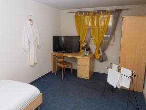 Schlafzimmer mit einem Bett und einem Schreibtisch mit einem TV in der Unterkunft Hotel Rhyhof in Frauenfeld