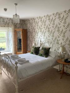 a bedroom with a white bed with a wall covered in wallpaper at The Punch Bowl Inn in Feetham