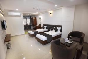 a hotel room with two beds and a table and chairs at Hotel Luxura, Ahmedabad in Ahmedabad