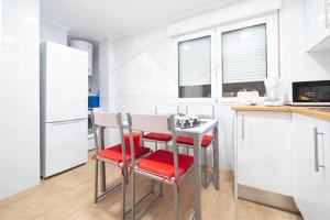 a kitchen with a table and two red chairs at Cruz Victoria By Silastur in Gijón