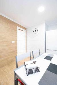 a kitchen with a white table with chairs and a refrigerator at Cruz Victoria By Silastur in Gijón
