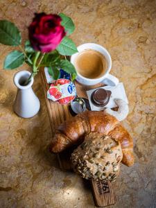 einen Tisch mit einer Tasse Kaffee, einer Rose und einem Gebäck in der Unterkunft Hotel Rhyhof in Frauenfeld