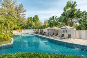 uma grande piscina com cadeiras e árvores em Dewa Phuket Resort & Villas em Praia de Nai Yang