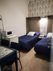 Habitación con 2 camas, mesa y microondas. en hospedaje barahona21, en León