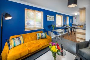 a living room with a yellow couch and a blue wall at Scarlet Oaks, easy walk from Hospital in Frimley