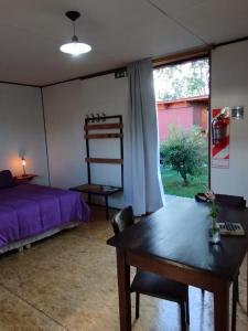 Schlafzimmer mit einem Bett, einem Tisch und einem Fenster in der Unterkunft vagones de la patagonia in El Calafate