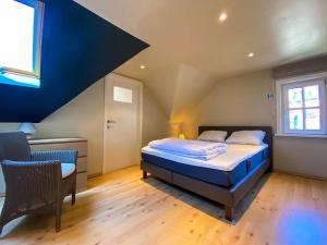 ein Schlafzimmer mit einem Bett und einem Stuhl auf einem Dachboden in der Unterkunft Villa Trianon -Summer beachhouse in De Panne