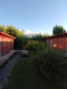 einen Hinterhof mit zwei Gebäuden und einem Picknicktisch in der Unterkunft vagones de la patagonia in El Calafate