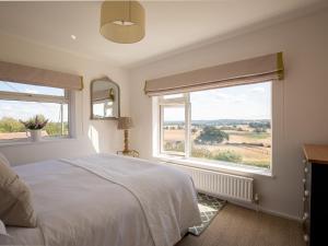 1 dormitorio con 1 cama blanca y 2 ventanas en Ridgeway Farmhouse, en Alcester