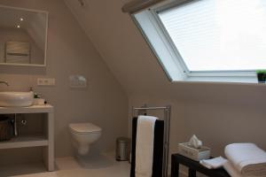 een badkamer met een wastafel, een toilet en een raam bij B&B Patrijzenhoek in Knokke-Heist
