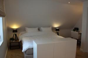 1 cama blanca en una habitación con 2 lámparas en B&B Patrijzenhoek en Knokke-Heist