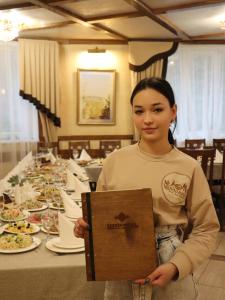 een vrouw met een bord voor een tafel bij База відпочинку ШИПОВЕЦЬ in Poroškov