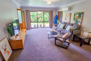 a living room with a couch and a tv at Tranquil Stream Villa in Rotorua