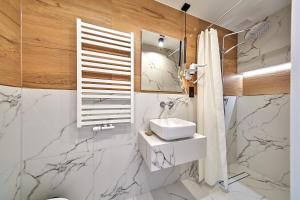 ein Badezimmer mit Marmorwänden, einem Waschbecken und einem Spiegel in der Unterkunft Leśny Dworek in Białka Tatrzańska