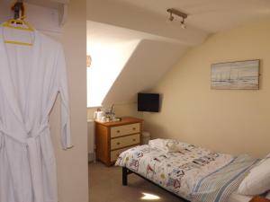 a bedroom with a bed and a robe hanging on a wall at The Edenhurst Guesthouse in Weymouth