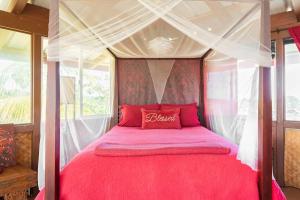 a bedroom with a red bed with a canopy at THE MAGICAL LAVA TEMPLE with EPIC Volcano Views! in Kehena